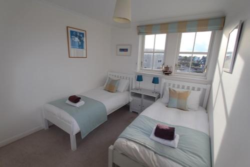 a bedroom with two beds and two windows at No 10 Royal Apartments in North Berwick