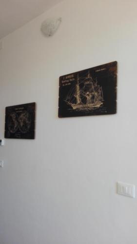 a white wall with three pictures of a ship on it at DiVino in Villa Viani
