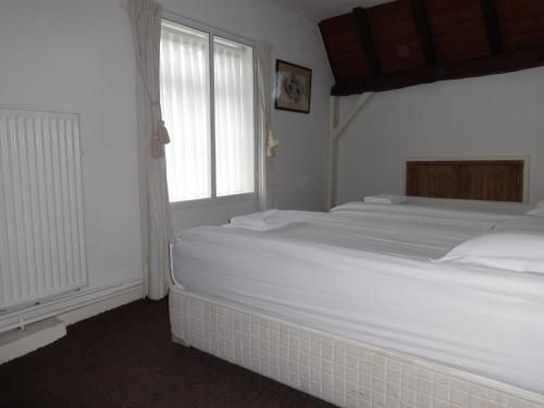 
a white bed sitting in a room next to a window at Bed and Breakfast Corvel in Tilburg
