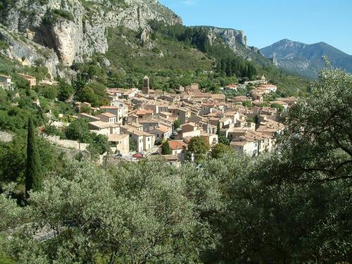a village on a hill with a mountain at Le Jas Du Colombier in Moustiers-Sainte-Marie