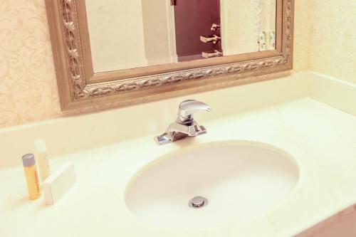 een wastafel in de badkamer met een spiegel en een kraan bij The Conwell Inn in Philadelphia