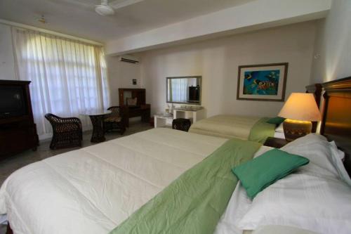 una camera d'albergo con due letti e una televisione di Mima's Village Cozumel a Cozumel