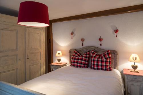 a bedroom with a bed with two red pillows on it at Gîtes de Charme Chez Christine in Ottrott