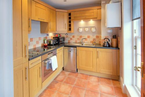 a kitchen with wooden cabinets and a tile floor at The Square in Kelso