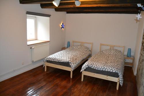 two beds in a room with wooden floors and a window at Gitesonoro Beho in Gouvy