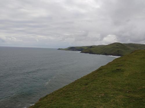 a grassy hill next to a body of water at Hillside View Guesthouse in Coffee Bay