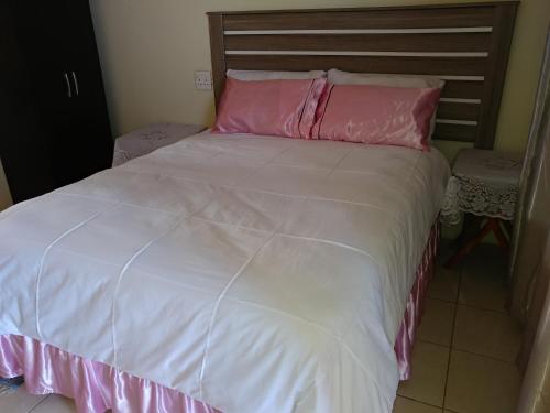 a large white bed with pink pillows on it at Hillside View Guesthouse in Coffee Bay