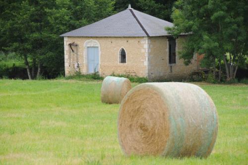 two large hay bales in a field in front of a building at Château de Mazières in Tendu