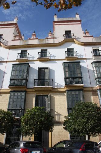 a large white building with windows and cars parked in front at La Casa del Consul in Cádiz