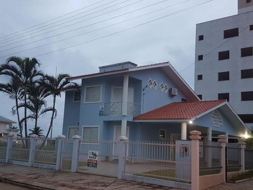 uma casa azul com uma cerca branca em frente em Casa de praia em Palmas-SC a 40 metros do mar em Governador Celso Ramos
