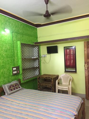 a bedroom with green walls and a bed and a chair at Nimmu Guest House & Restaurant Gokarna in Gokarna
