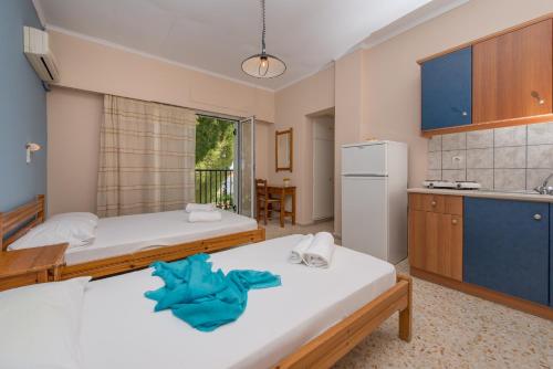 two beds in a room with a kitchen at Helen & Theo in Laganas