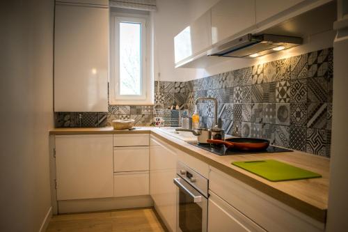 cocina con armarios blancos, fregadero y ventana en Au jardin des plantes, en Dijon