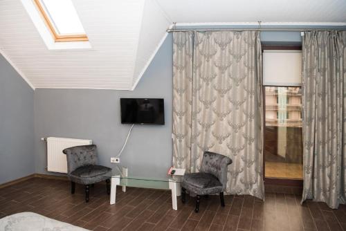 a room with two chairs and a table and a tv at Hotel " BOUTIQUE " in Uzhhorod