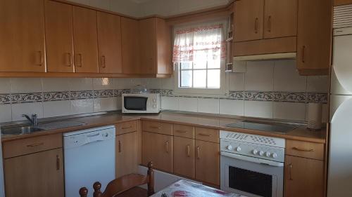 a kitchen with wooden cabinets and a white appliances at La Puente 9 de Gredos in Hoyos del Espino