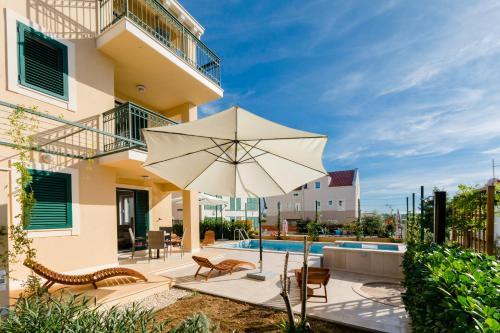 eine Terrasse mit einem Sonnenschirm und einem Pool in der Unterkunft Vila Mimoza in Milna
