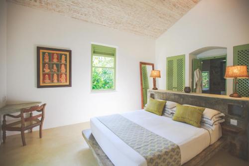 a bedroom with a bed and a table and a window at Karmel Villa Thalduwa Island - Five Bedroom Luxury Villa with Private Pool in Ahangama