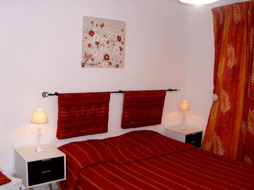 a bedroom with a bed with red sheets and two lamps at Studio Des Iles in Saint-François