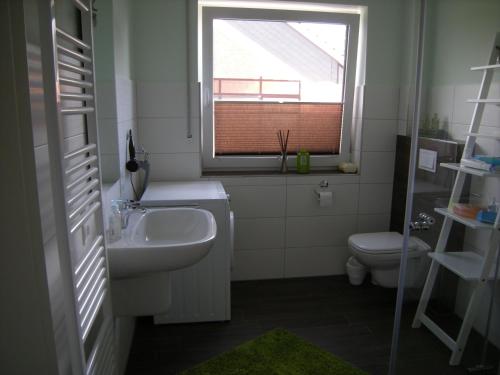 a bathroom with a sink and a toilet and a window at Strandgut in Horumersiel