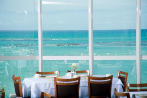 a table in a room with a view of the ocean at Hotel Brisa Praia in Maceió