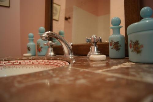a bathroom sink with a faucet and blue bottles on it at Logis Hotel - Restaurant La Marbrerie in Caunes-Minervois