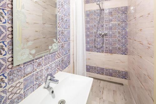ein Badezimmer mit einem weißen Waschbecken und blauen Fliesen in der Unterkunft Lovely apartment in the city center in Lwiw