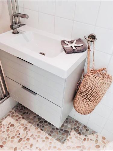 a bathroom with a white sink and a basket at ELSK Cottage in Zandvoort