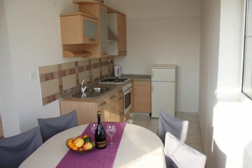 una cucina con tavolo e ciotola di frutta di Apartment Arba 3 s bazenom i parkingom a Rab