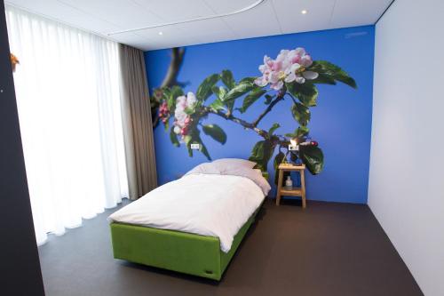 de rode beer (zeer rolstoelgeschikt) في Heerde: غرفة نوم مع سرير مع شجرة على الحائط