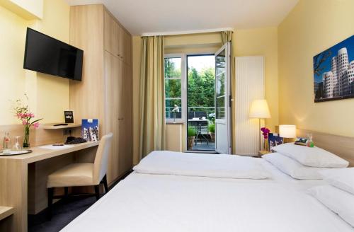 a hotel room with two beds and a desk and a window at Hotel am Hofgarten in Düsseldorf
