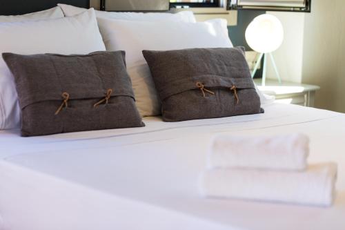 a white bed with two brown pillows on it at Philoxenia Villas in Panormos Rethymno