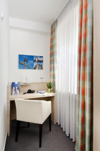 an office with a desk with a chair and a window at Hotel am Hofgarten in Düsseldorf