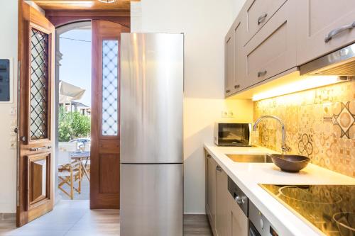a kitchen with a stainless steel refrigerator in front of a door at Philoxenia Villas in Panormos Rethymno