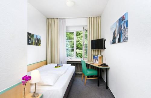 a hotel room with a bed and a desk at Hotel am Hofgarten in Düsseldorf