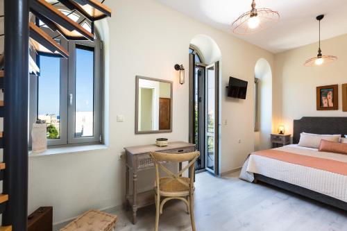a bedroom with a bed and a desk and windows at Philoxenia Villas in Panormos Rethymno