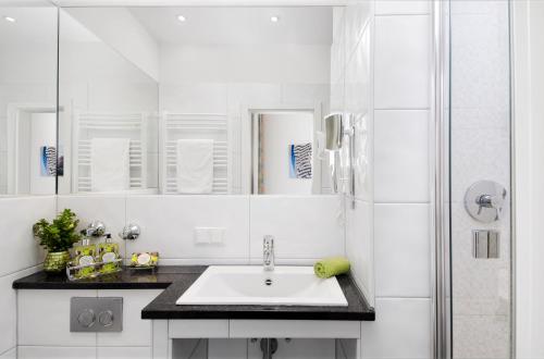 a white bathroom with a sink and a shower at Hotel am Hofgarten in Düsseldorf