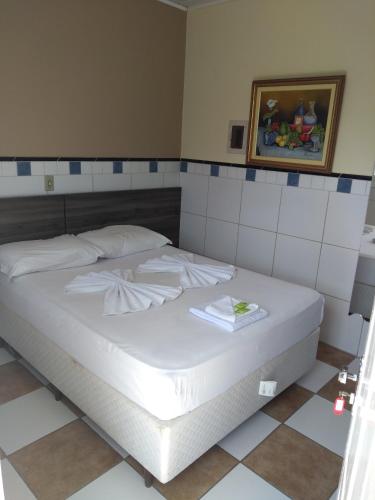 a white bed in a room with a picture on the wall at Ville House Hotel Canoas in Canoas
