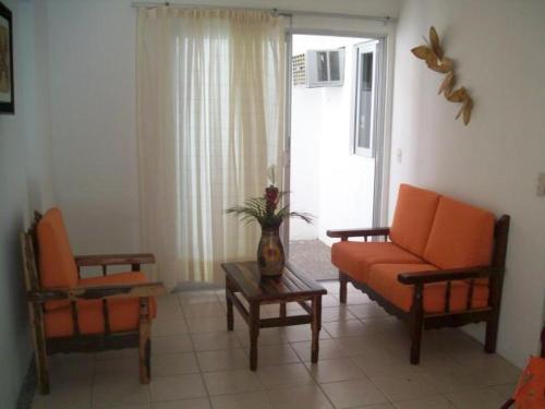 a living room with an orange couch and two chairs at Hotel y Suites Corita in Bucerías