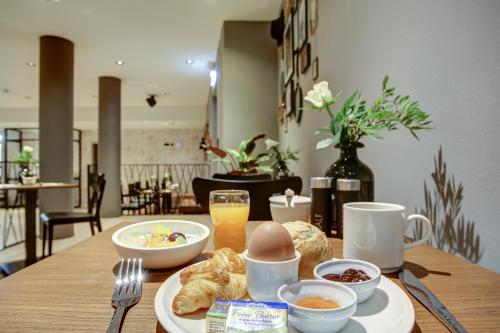 a wooden table with breakfast foods and drinks on it at NYCE Hotel Hamburg City in Hamburg