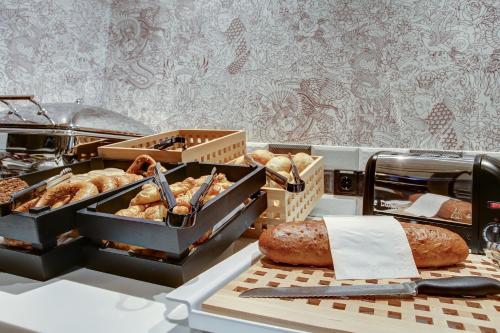 a table with trays of bread and pastries on it at Vienna House Easy by Wyndham Hamburg City in Hamburg