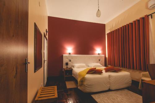 a hotel room with a bed and a red wall at Palmeiras Guest House Maputo in Maputo
