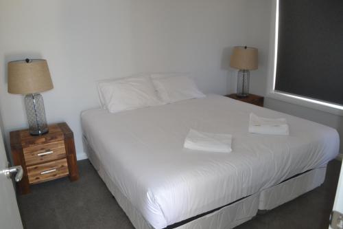 a bedroom with a white bed with two lamps and a window at Yarrawonga Holiday Park in Yarrawonga
