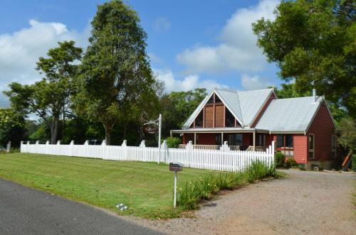 a red house with a white fence in front of it at Ruddles Retreat in Maleny