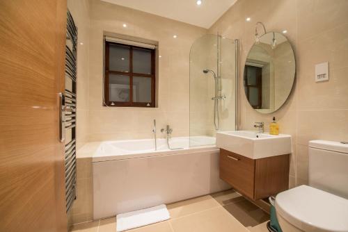 a bathroom with a tub and a sink and a mirror at Hampden Apartments - The Catherine in Windsor