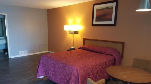 a bedroom with a bed and a table and a lamp at Town'n Country Motor Inn in Leamington