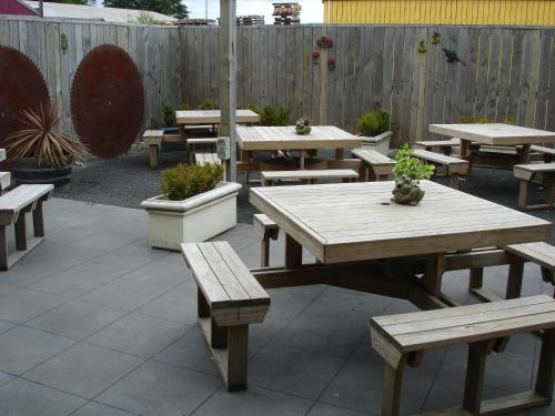 a group of picnic tables and benches with a fence at Horse and Jockey Inn in Matamata
