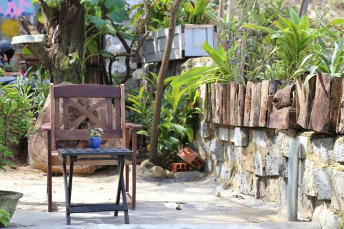 a chair and a table in front of a stone wall at Confetti House in Quy Nhon