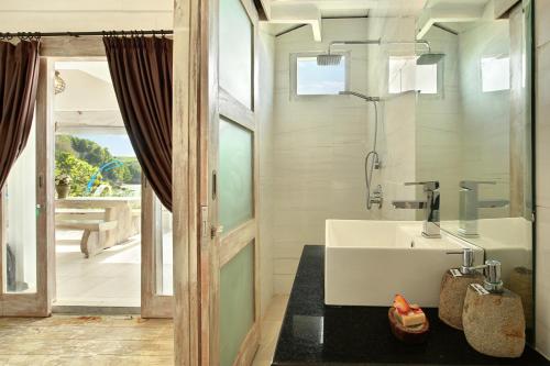 Łazienka z białą umywalką i szklanymi drzwiami w obiekcie The Point Beach-Front Balangan w mieście Jimbaran