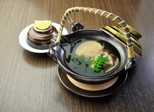 a bowl of soup on a table with a plate of food at Ito Yukitei in Ito