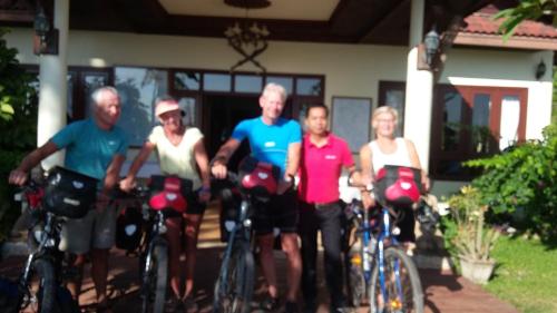 a group of people on bikes in front of a house at Senesothxuene Hotel in Muang Không